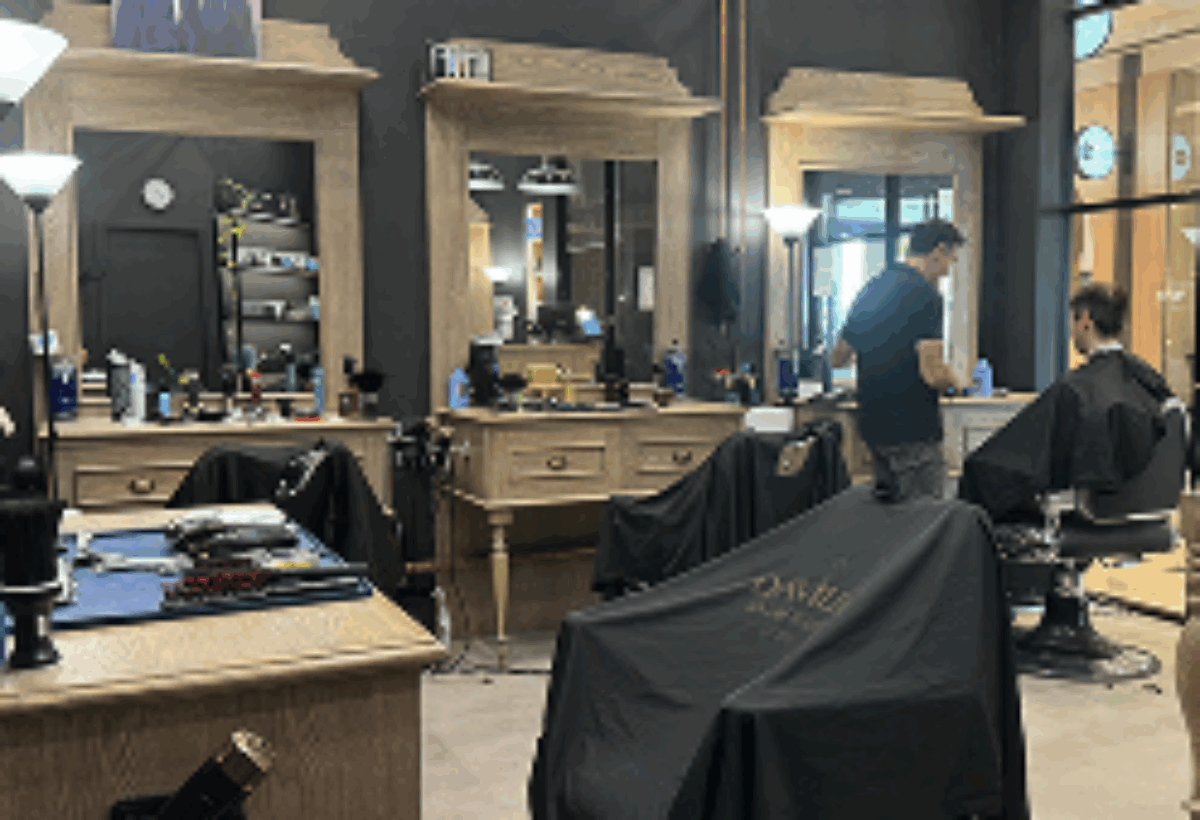 Davilia Location - Karrinyup's interior with wooden styling stations, and a barber cutting a client’s hair.